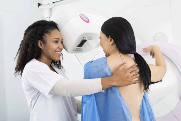 Happy Doctor Assisting Woman Undergoing Mammogram X-ray Test missed cancer screenings