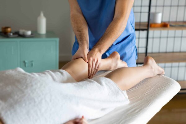 Professional physiotherapist massaging woman calves in spa cente