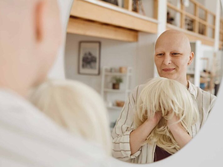 Bald Woman Smiling at Mirror Winter Wig Care